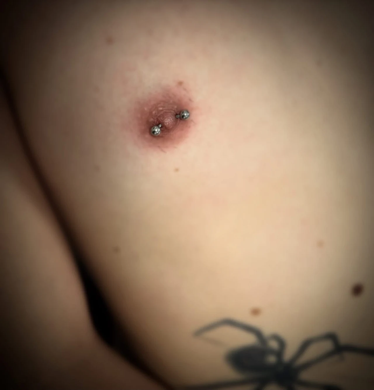 Sachliche Detailaufnahme eines Brustwarzenpiercings